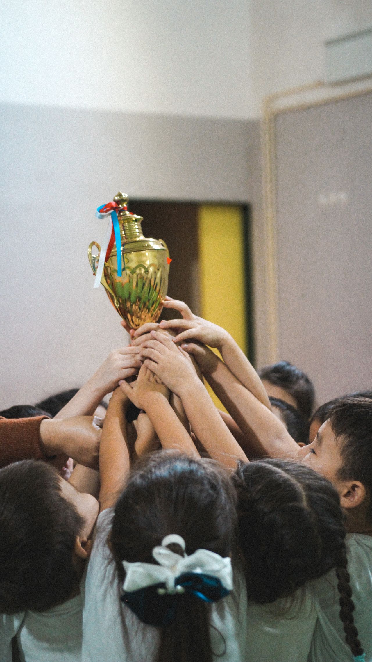 Group of children lifting a golden trophy celebrating achievement