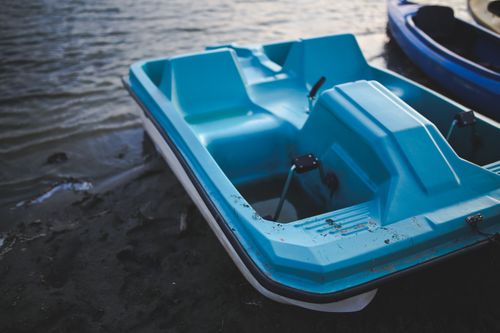 Free A blue pedalo sits by the water's edge on a tranquil sandy beach, perfect for summer recreation. Stock Photo