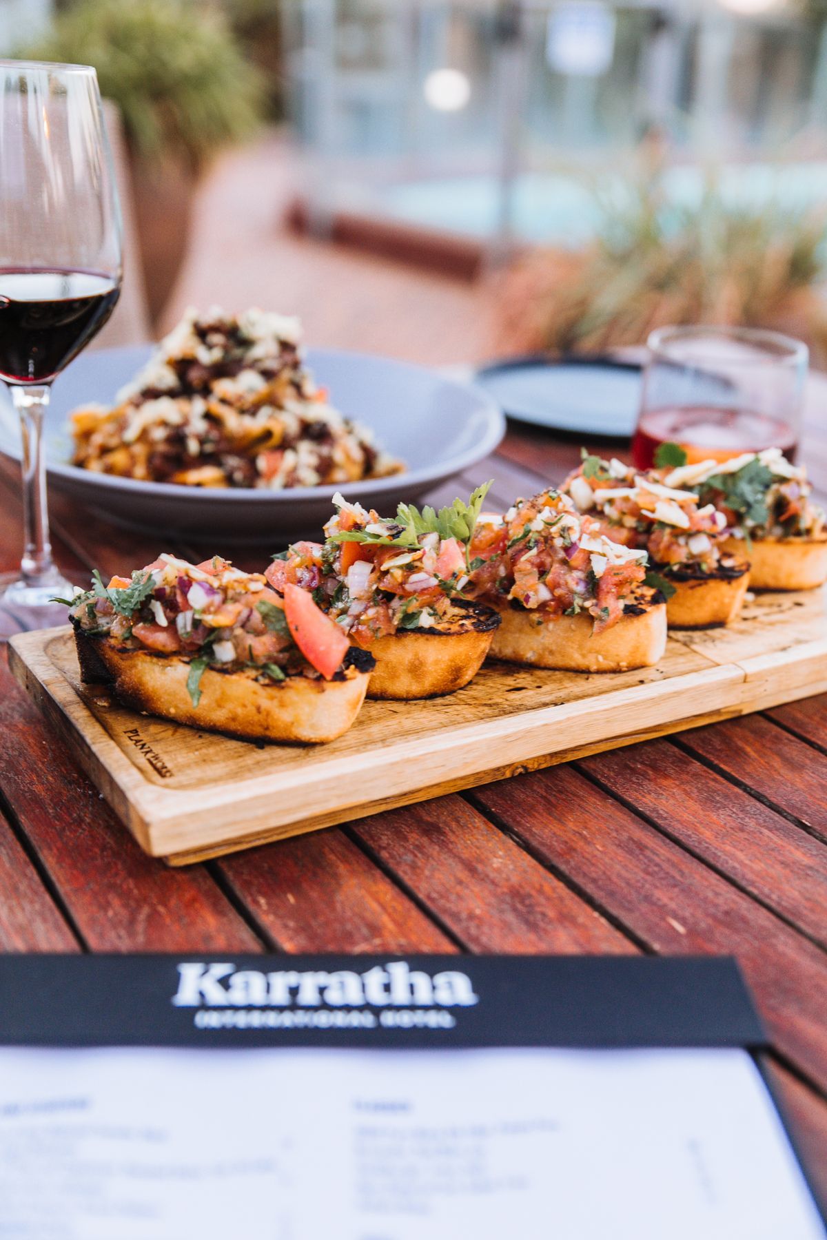 Bruschetta on a wooden board with a glass of wine, a party-bite spread