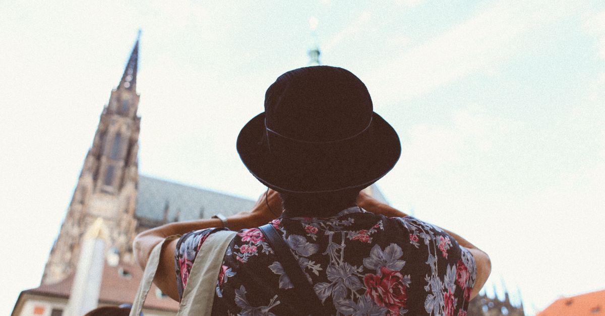 Traveler wearing floral shirt and hat captures historic church. Perfect for travel concepts.