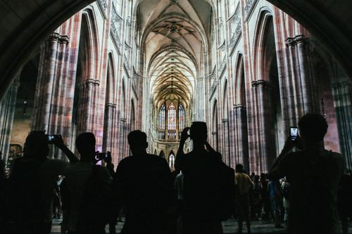 Free A stunning view of a Gothic cathedral's interior with silhouetted tourists capturing its grandeur. Stock Photo