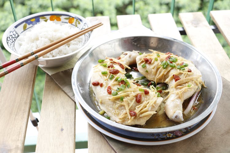 A Chicken Dish And Bowl Of Rice On Wooden Table