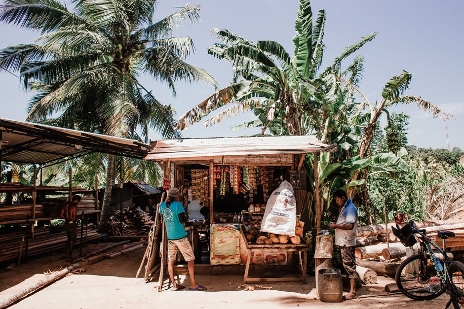 Photo by Rachel Claire A small shop in a tropical locale sells goods under the bright daytime sun.