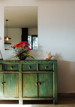 Stylish room with a vintage green cabinet, flower vase, and decorative shell.