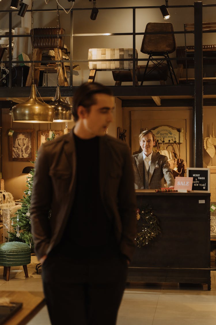 A Man Standing Behind The Counter Of A Furniture Shop