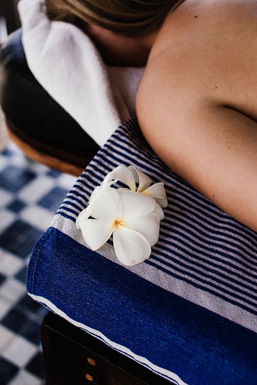 Free Close-up of a woman on a massage table with a white flower for a serene spa atmosphere. Stock Photo