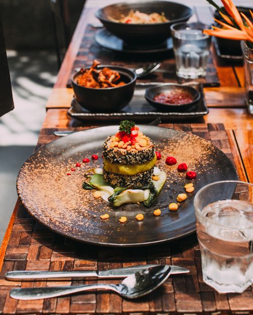 Free Delicious gourmet vegetarian dish beautifully plated with artistic garnish on a stylish wooden setup. Stock Photo
