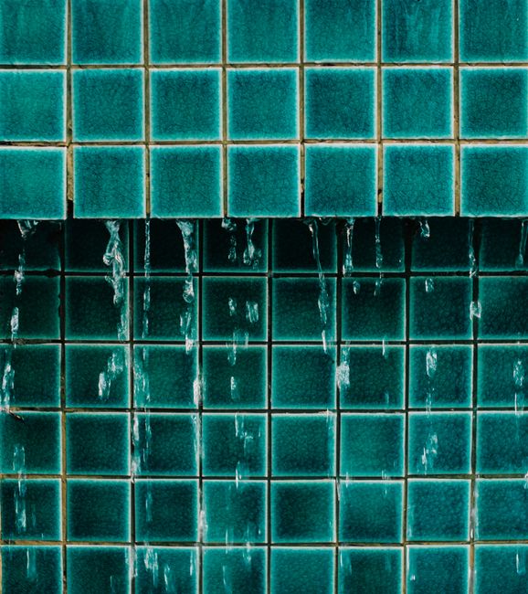 A detailed view of water dripping over blue geometric tiles, showcasing pattern and texture.