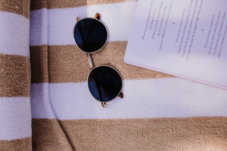 A Sunglasses Beside A White Paper On A Towel