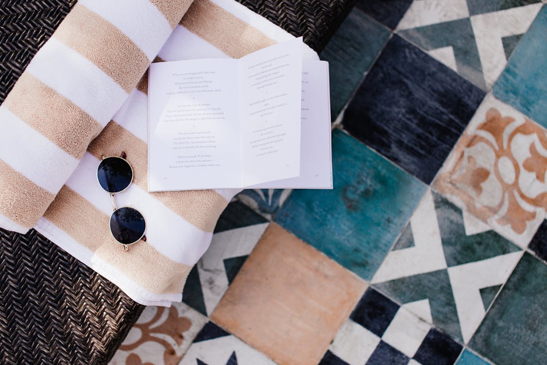 Free Overhead Shot of Sun Glasses and a Book on the Bath Towel Stock Photo