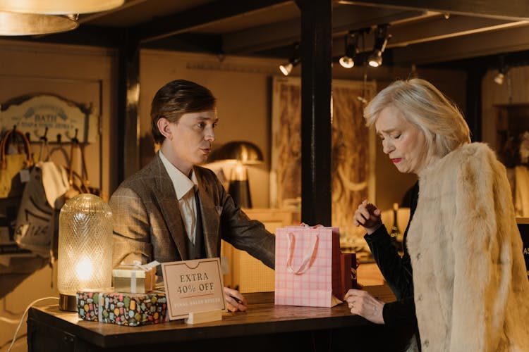 A Salesman Talking To A Woman Wearing A Fur Coat