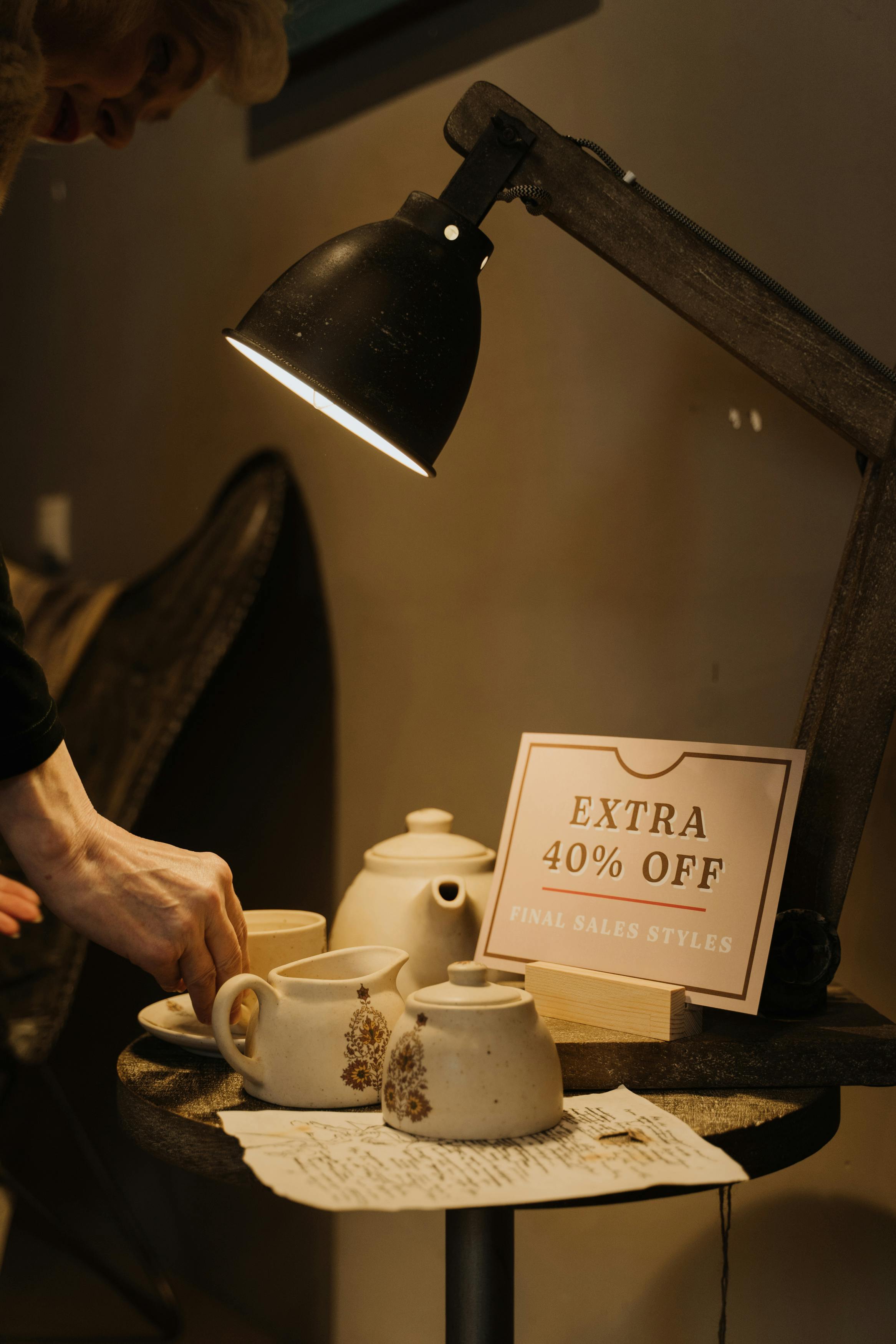 Rustic display of ceramic teapots and cups under warm light with a 40% discount sign.
