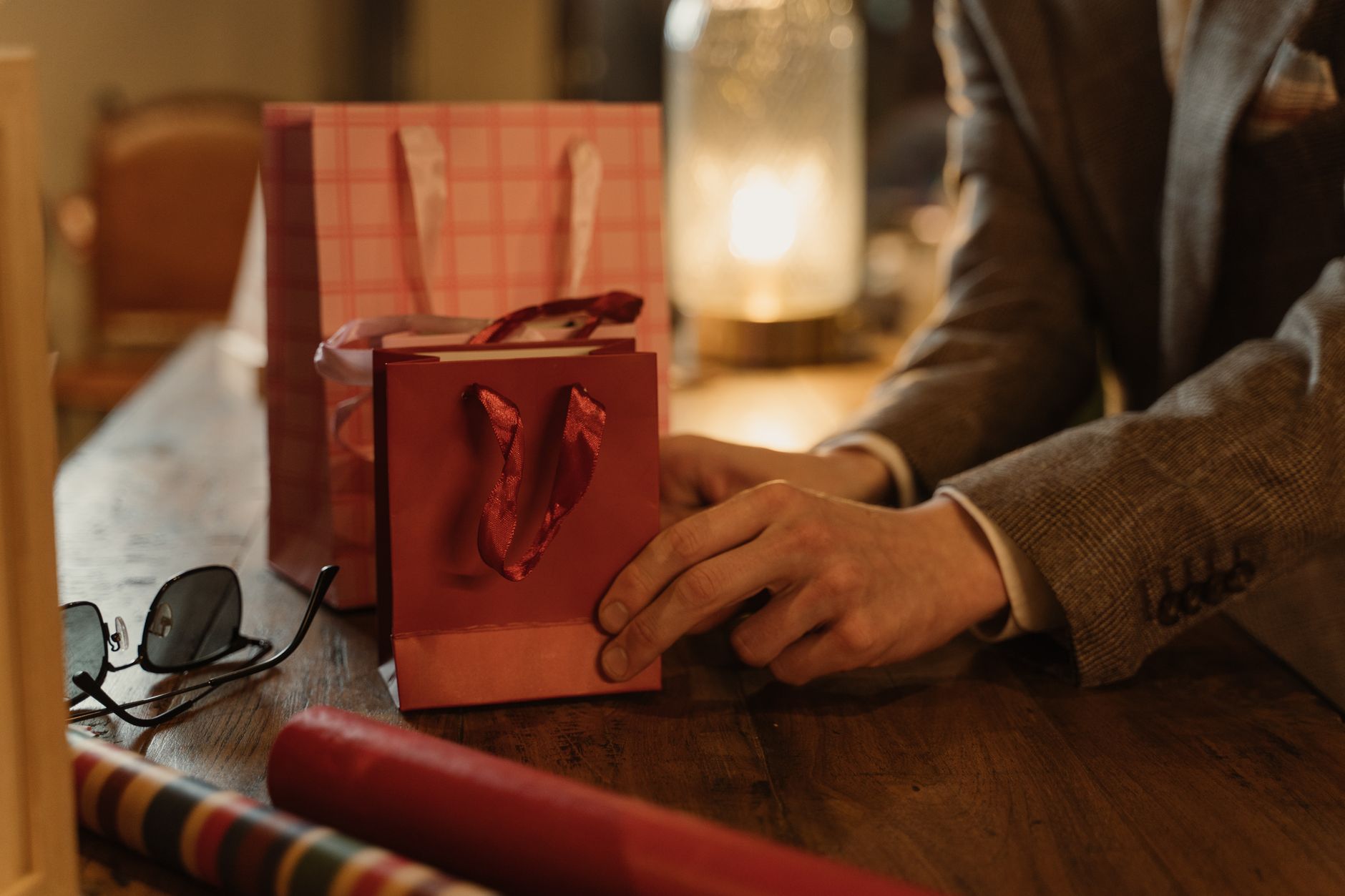 Close-up of hands arranging gift bags on a wooden table, ideal for commerce and business themes.