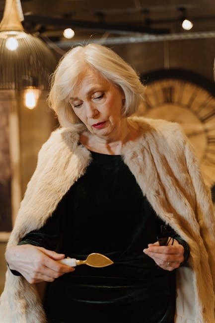 Sophisticated senior woman in a luxurious fur coat and black dress examining a chisel indoors.