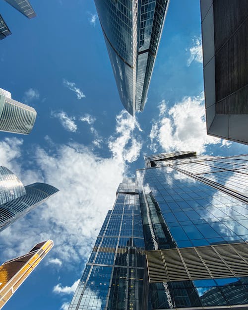 From below of contemporary high skyscrapers with mirrored glass walls located in Moscow city Russian Federation on partly cloudy day