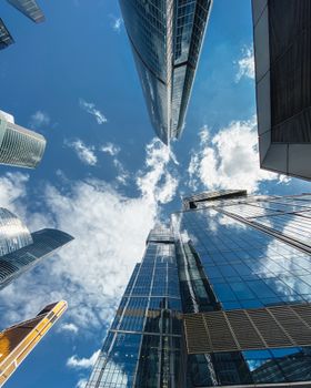 From below of contemporary high skyscrapers with mirrored glass walls located in Moscow city Russian Federation on partly cloudy day