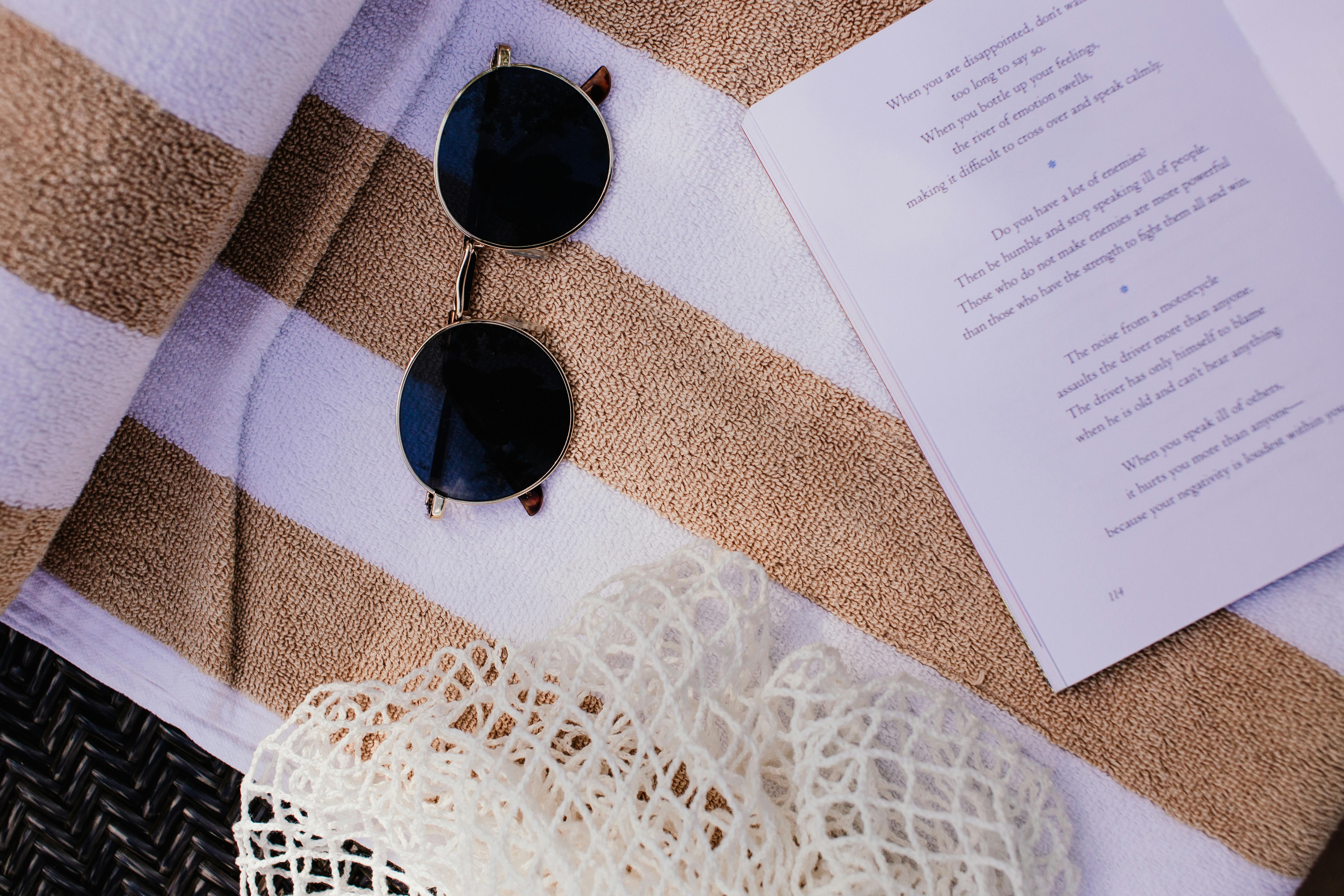 舒适的布置，包括书、太阳镜和条纹毛巾，非常适合海滩旅行