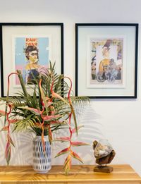 Chic room showcasing vibrant framed art and tropical plant on wooden table.