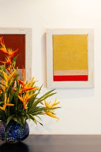 A colorful flower arrangement in a vase next to abstract paintings on a wall, creating a vivid indoor scene.