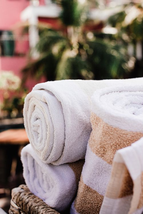 Free High-quality cotton bath towels stacked outdoors, perfect for a relaxing spa day. Stock Photo