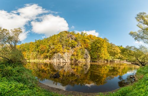 Free Peaceful autumn scene of a lake reflecting vibrant foliage and clear skies. Stock Photo