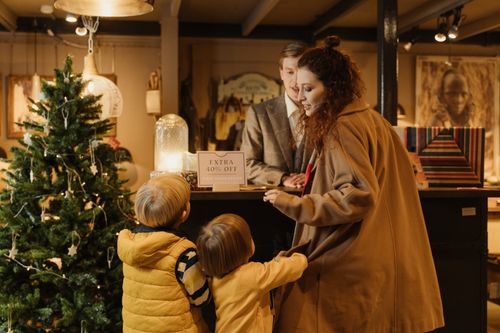 Free Family enjoying holiday shopping at a decorated store with a Christmas tree and sale offer. Stock Photo
