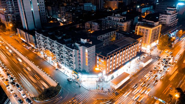 Dynamic aerial cityscape showing illuminated intersection and buildings at night.
