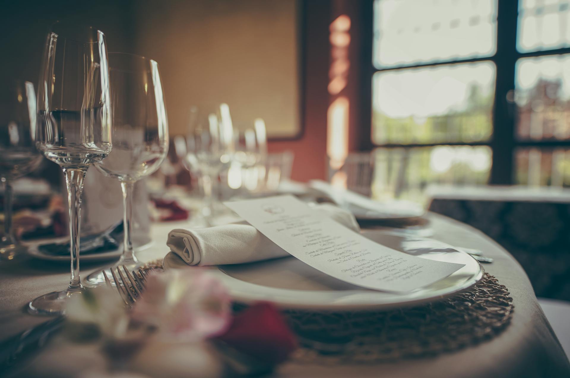 A cozy indoor fine dining table setup with elegant tableware and a stylish menu under warm lighting.