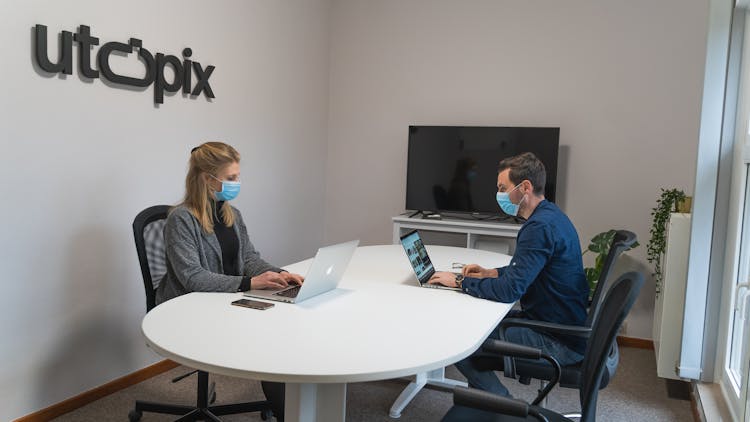 Employees Wearing Face Mask In The Office Busy Working With Their Laptops