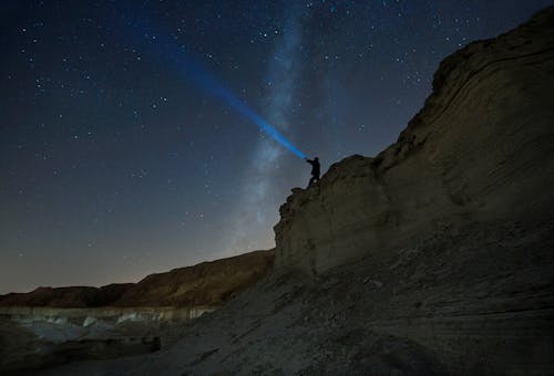 Free A Person Standing on Rock Formation Holding Flashlight Stock Photo