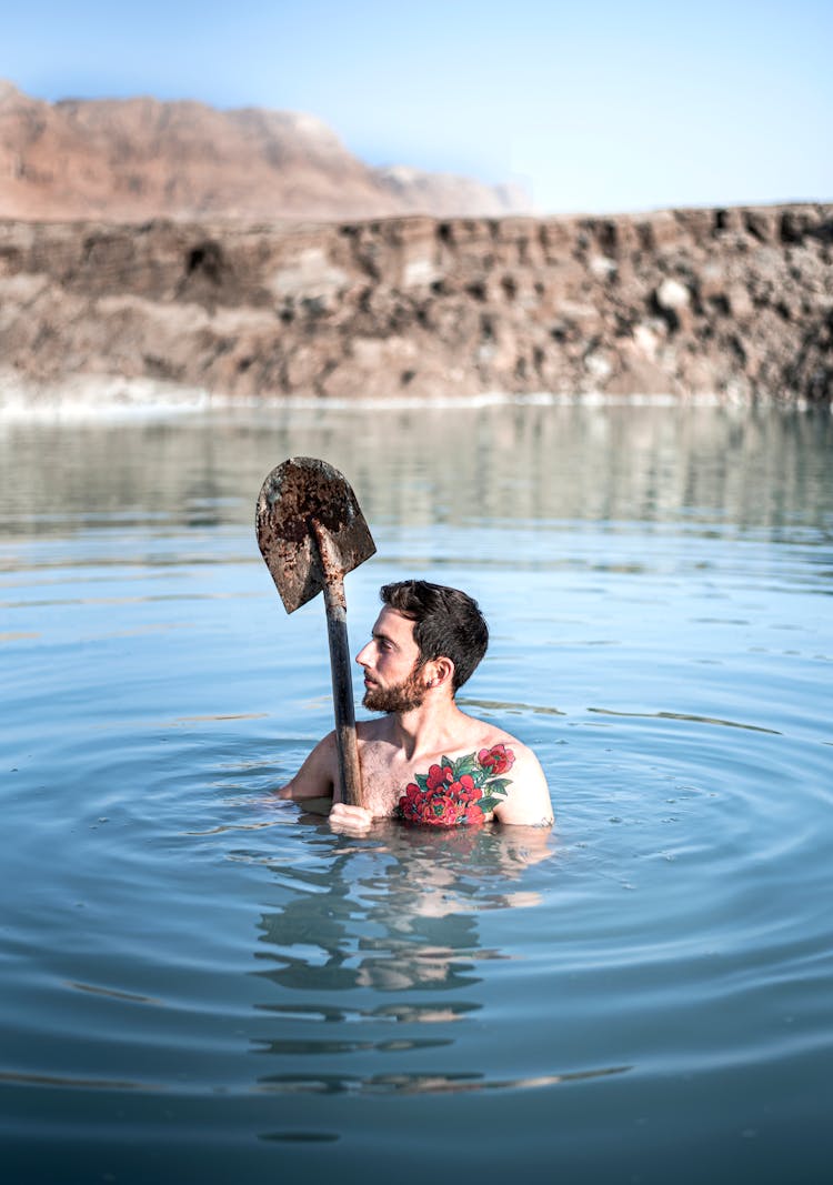 A Man Holding A Shovel While In Water