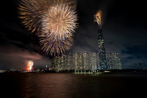 Beautiful shiny fireworks exploding in night sky over big modern megapolis with high skyscrapers