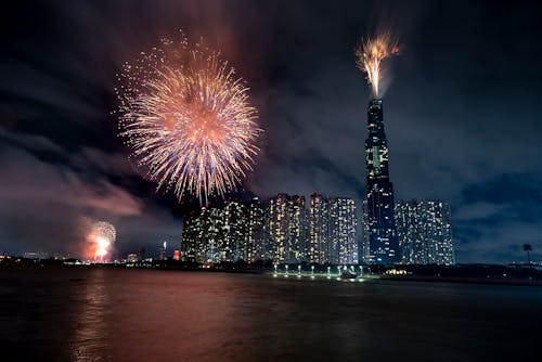Big megapolis on shore of river and fireworks in sky