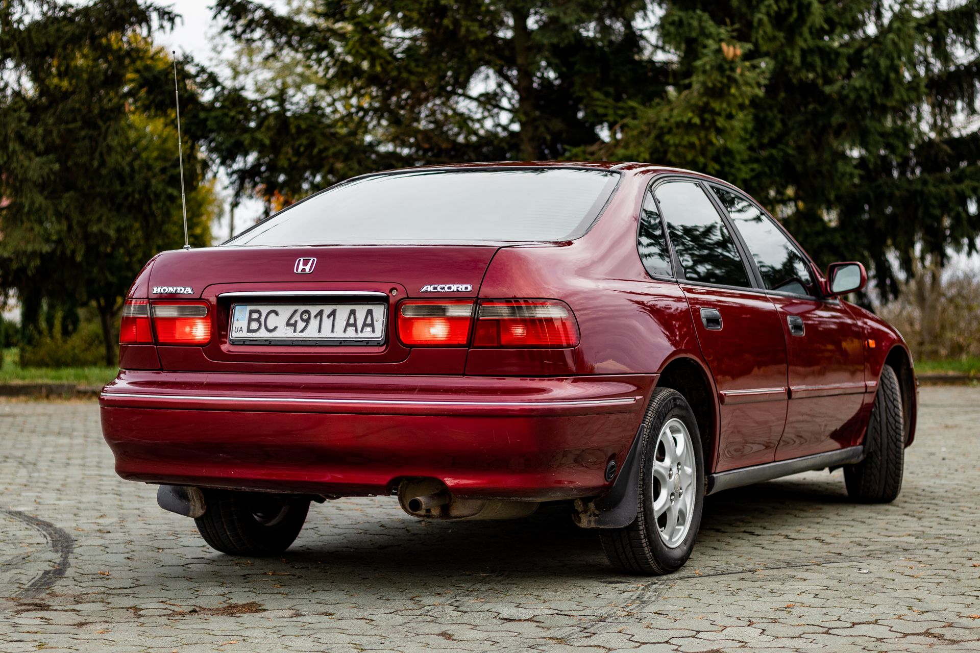 Rear view of a shiny red Honda Accord sedan parked outdoors on a paved area.