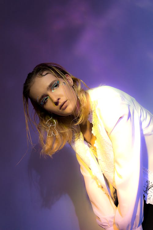 Side view of young woman in white shirt bending down and looking away in room