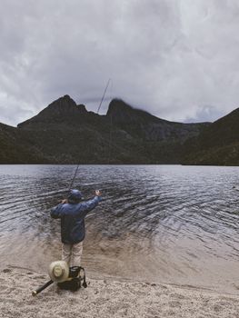 A man enjoying a peaceful fishing day at Cradle Mountain Lake, Tasmania, surrounded by stunning nature.