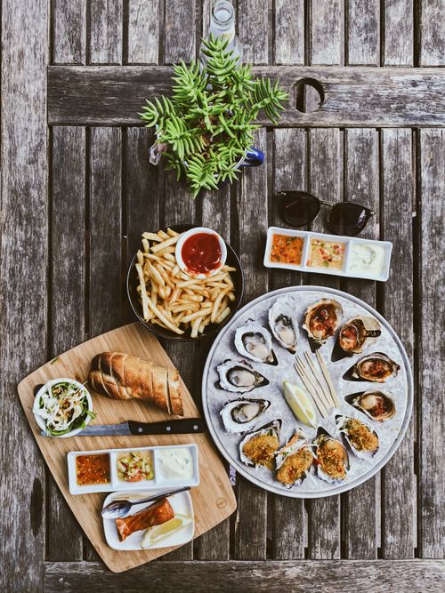Free Delicious seafood platter featuring oysters, fries, and sauces in an outdoor dining setting. Stock Photo