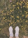 A Person Wearing a Pair of White Shoes on a Flower Field