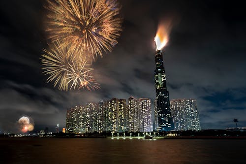 Night cityscape with illuminated skyscrapers and fireworks near river