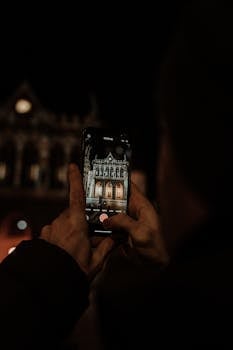 A person capturing a historic building in Erfurt, Germany using a smartphone at night.