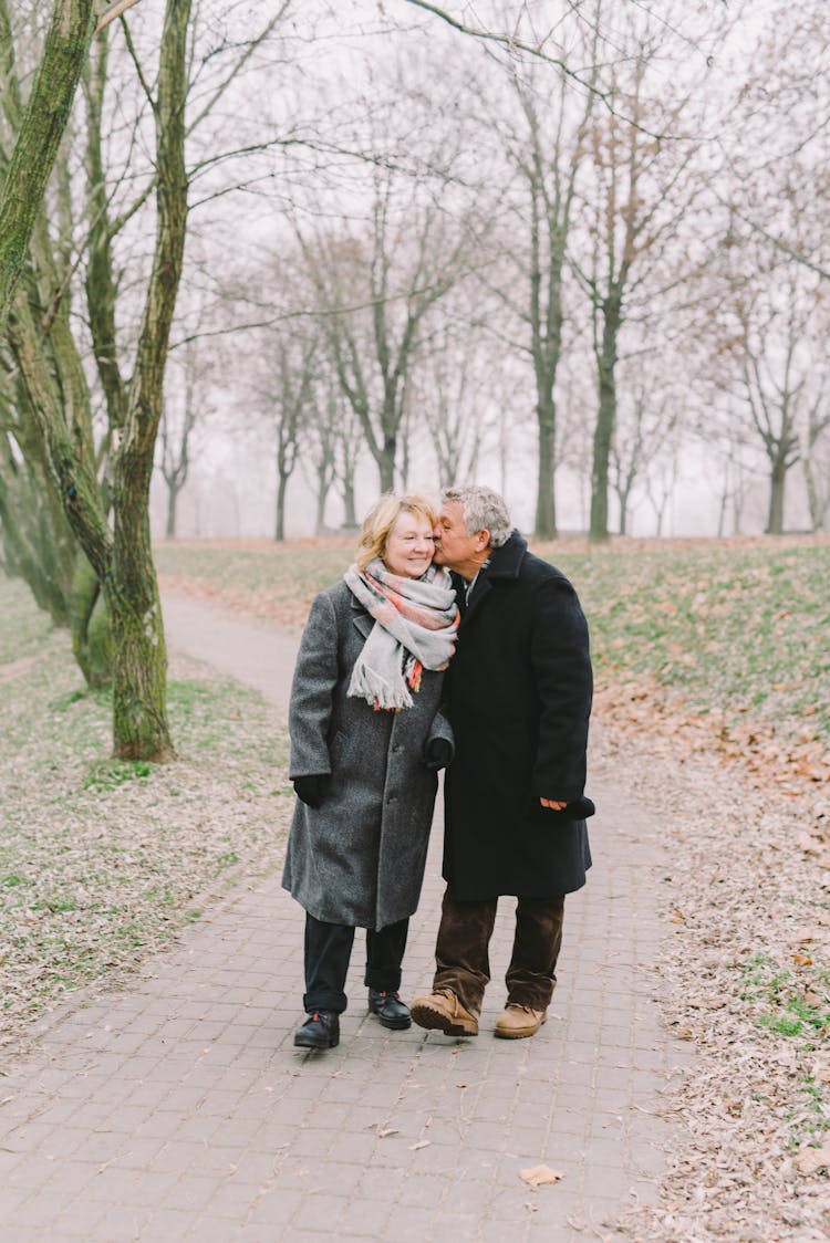 Man Kissing A Woman While Walking In The Park