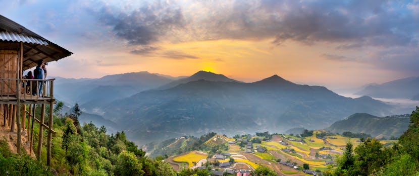 Group of people enjoying picturesque view of small settlement  near mountains covered with lush green trees against cloudy sky in rocky valley