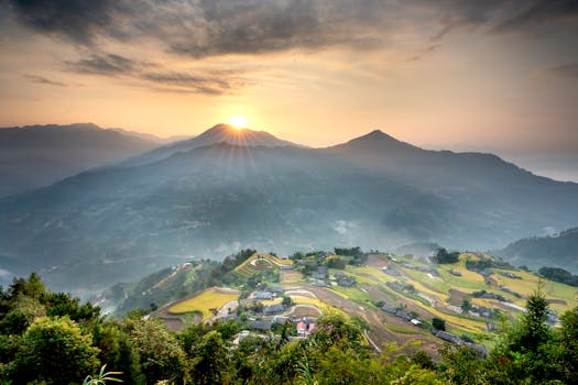 Breathtaking sunrise over terraced farms with mountains, showcasing rural beauty.