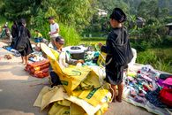Asian people standing near indigenous market with goods on ground