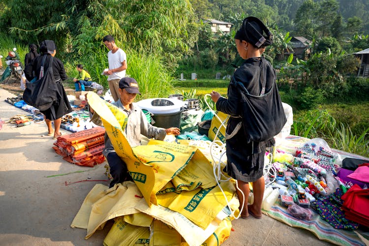 Asian People Standing Near Indigenous Market With Goods On Ground