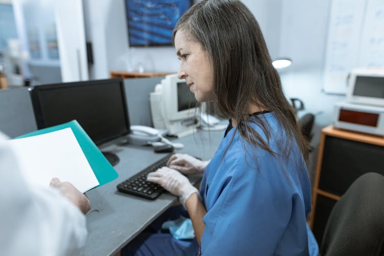 A Nurse Typing On A Keyboard While Sitting