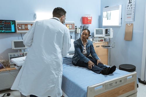 Doctor Talking to a Patient Sitting on Bed