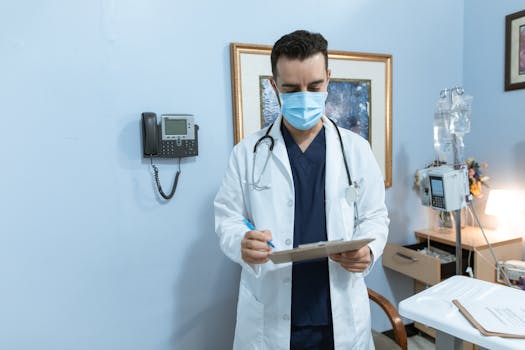 Healthcare professional in hospital reviewing medical chart with protective mask and stethoscope.