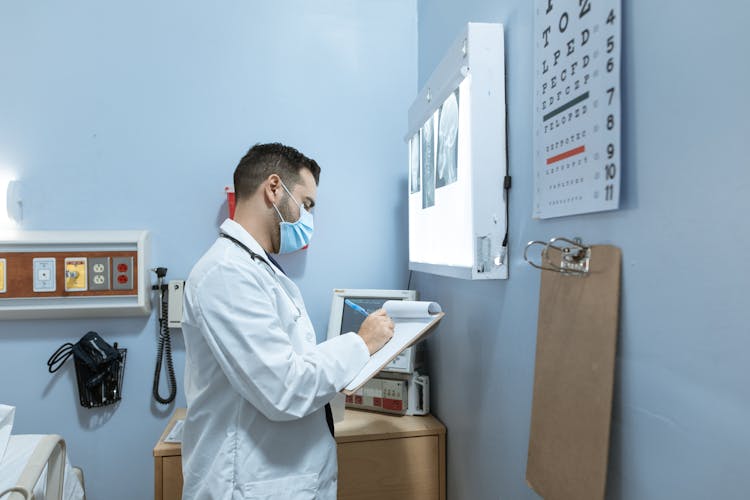 Doctor Writing On A Medical Chart