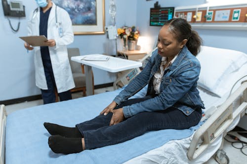 Vrouw In Blauw Denim Jasje En Zwarte Denim Jeans Zittend Op Wit Bed